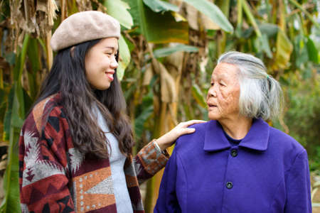 Asian girl spending time outdoors with her grandma in green tropical environmentの写真素材