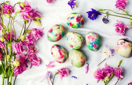 Easter eggs and colorful iris flowers on white textile backgroundの写真素材