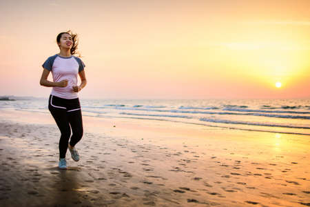 Girl running on the beach at sunset, outdoors workoutの写真素材