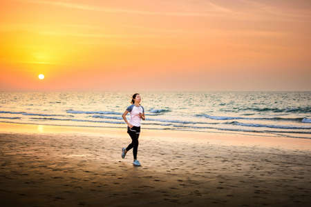 Girl running on the beach at sunset, outdoors workoutの写真素材