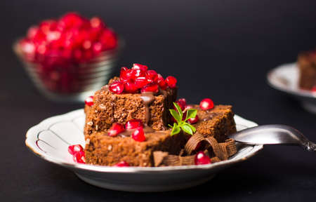 Chocolate cake with pomegranate on plate close upの写真素材