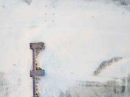 Wooden dock on a empty beach aerial view at sunriseの写真素材