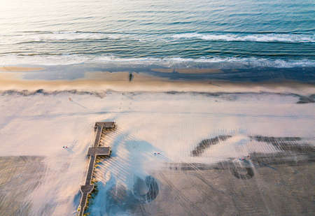 Wooden dock on a empty beach aerial view at sunriseの写真素材