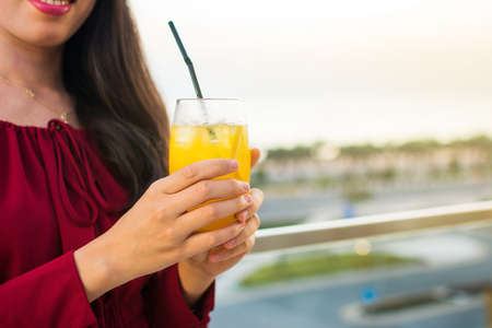 Girl having a drink on the restaurant balcony at sunsetの写真素材