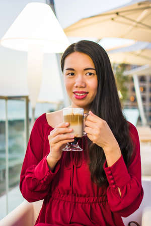 Girl having a cup of coffee in a bar at sunsetの写真素材