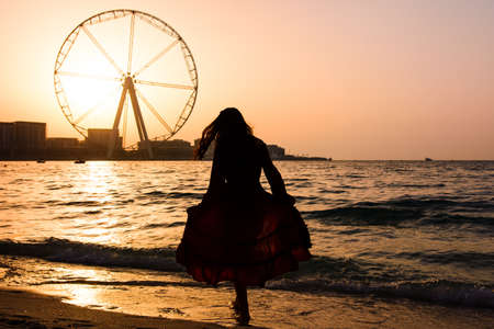 Girl on the JBR beach with Ain Dubai ferris wheel at sunsetの写真素材