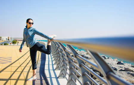 Girl warming up for a workout by the seaside. Active lifestyle