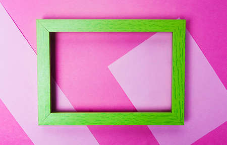 Green photo frame on pink background top view