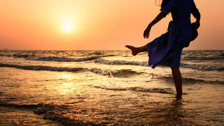 Silhouette of a woman on the beach at sunsetの写真素材