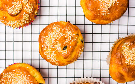 Homemade sesame muffins with seeds and grains on a baking netの写真素材