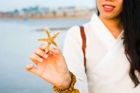 Female holding a starfish on the beach at sunsetの写真素材