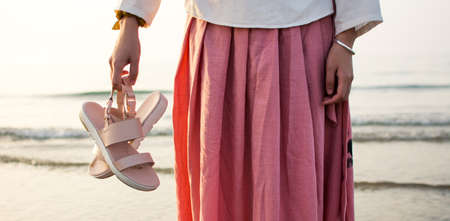 Girl holding sandals on the beach close upの写真素材