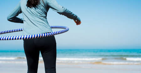 Girl exercising with hoop on the beach close upの写真素材