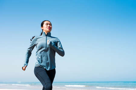 Girl running on the beach at sunny morningの写真素材
