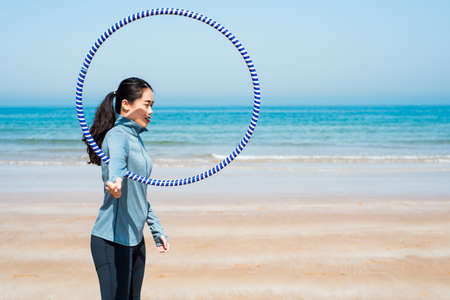 Happy woman exercising with hoop on the beachの写真素材