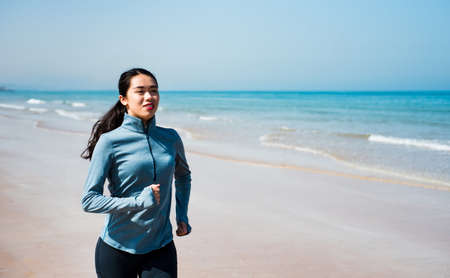 Girl running on the beach at sunny morningの写真素材