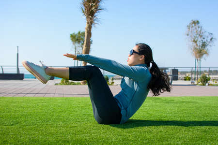 Girl doing situps on the grass, outdoors workoutの写真素材