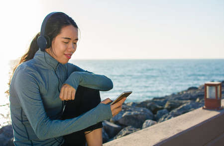 Girl listening to music sitting by the seaside and enjoying sunny dayの写真素材