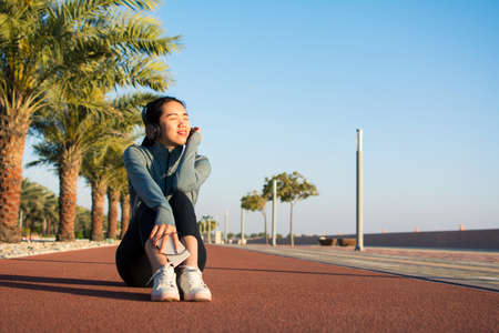 Girl sitting on a running track and taking a break from workout