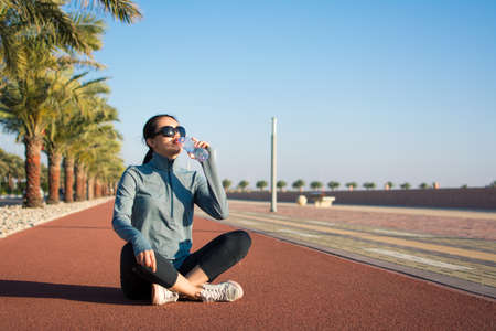 Girl taking a break from workout on a running trackの写真素材