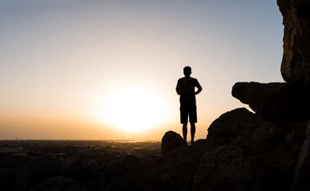 Hiker on the mountain top facing the sunset, silhouette shootの写真素材