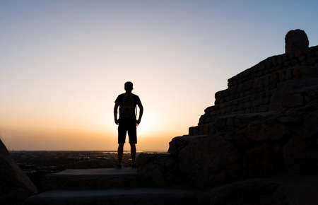 Male hiker on the mountain top silhouette shot at sunsetの写真素材