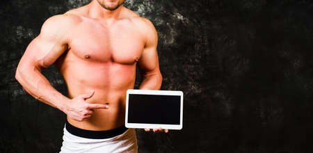 Male bodybuilder holding a tablet device with copy spaceの写真素材