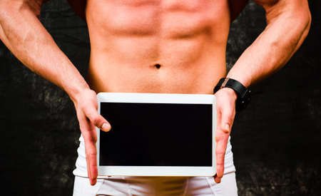 Bodybuilder holding a tablet device with copy spaceの写真素材