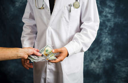 Doctor accepting money bills close up, bribery concept
