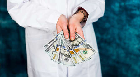Female doctor holding many dollar bills close upの写真素材