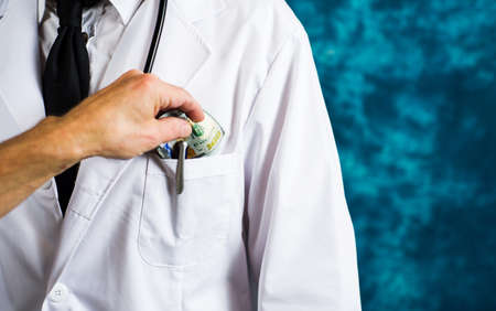 Doctor accepting money bills close up, bribery conceptの写真素材
