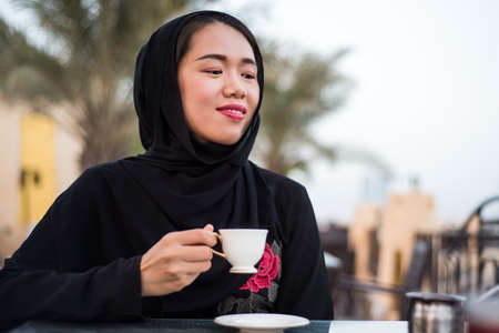 Muslim woman having a cup of coffee in a bar outdoorsの写真素材