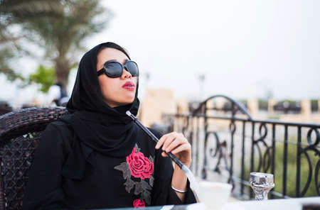 Muslim woman smoking shisha in a bar outdoors