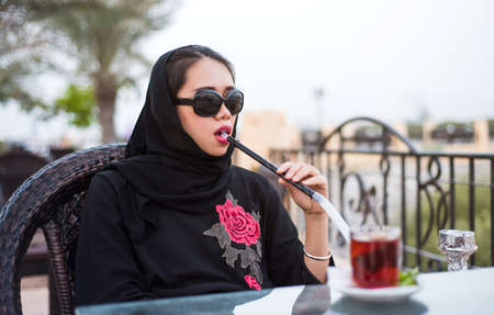 Muslim woman smoking shisha in a bar outdoorsの写真素材
