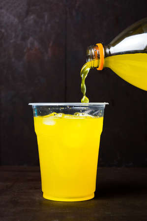 Orange juice poring in a plastic cup with iceの写真素材