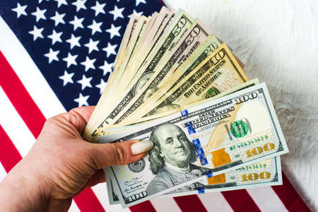 Hand holding dollar bills against American flagの写真素材