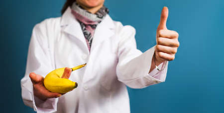 Female doctor holding a banana close upの写真素材