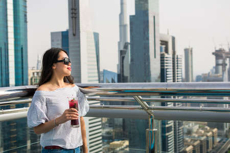 Girl having a drink with Dubai city view