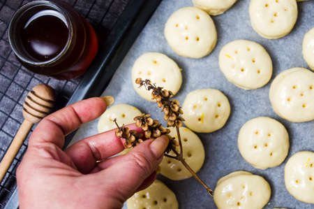 Hand holding dry basil above pastry dough for honey bunsの写真素材