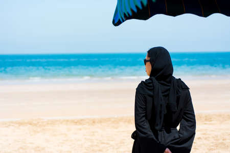 Muslim woman on the sunny beach back viewの写真素材