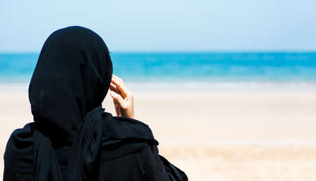 Muslim woman on the sunny beach back viewの写真素材