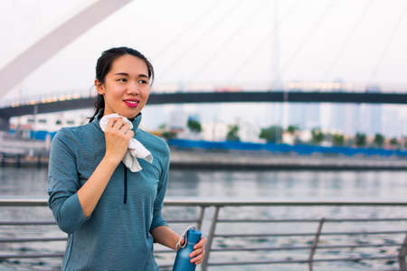 Tired girl wiping out sweat after workoutの写真素材