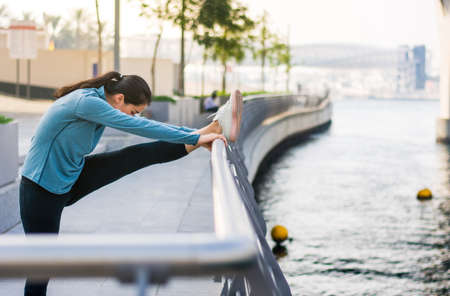 Girl stretching with music before running in urban environment