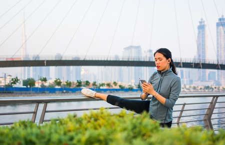 Girl stretching with music before running in urban environment
