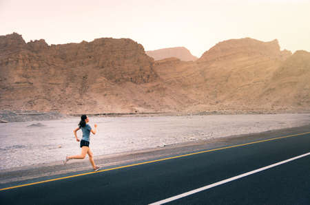Girl running on the desert road, outdoor workoutの写真素材