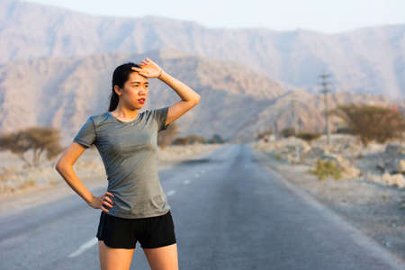 Tired runner taking a rest on a desert roadの写真素材
