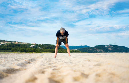 Tired senior taking rest during exercise on the beach, active lifestyleの写真素材