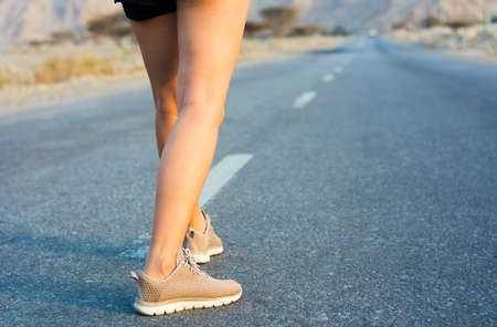 Female runner on the desert road low angle view