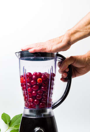 Person making cherry smoothie with a blender isolatedの写真素材