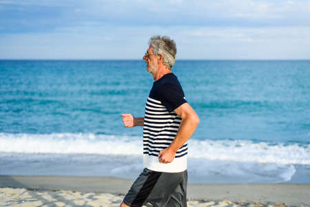 Senior man running on the beach, active vacation lifestyleの写真素材